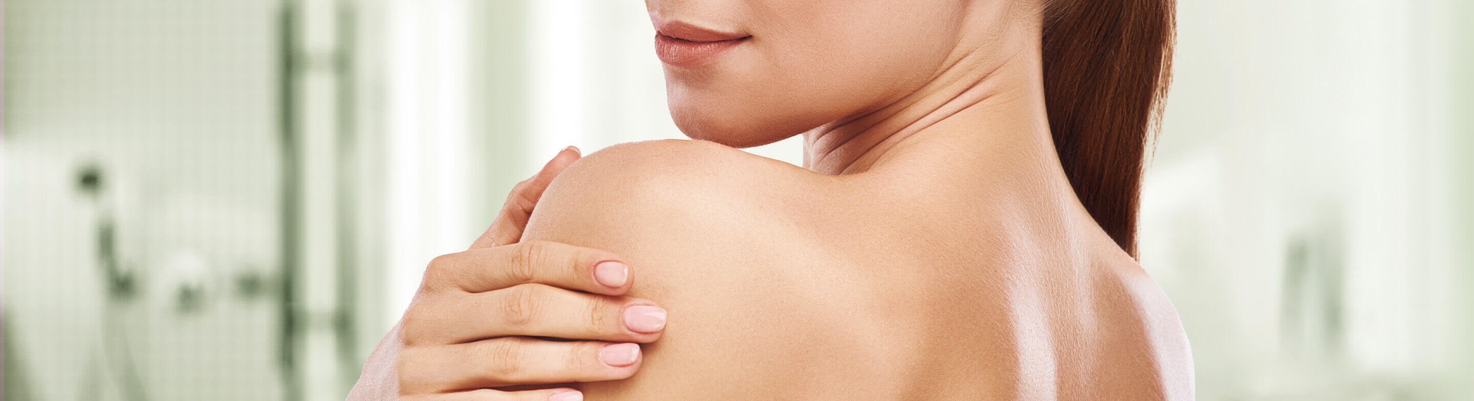 mujer sonriente con un paño exfoliante espumoso en la mano tomando la ducha en casa